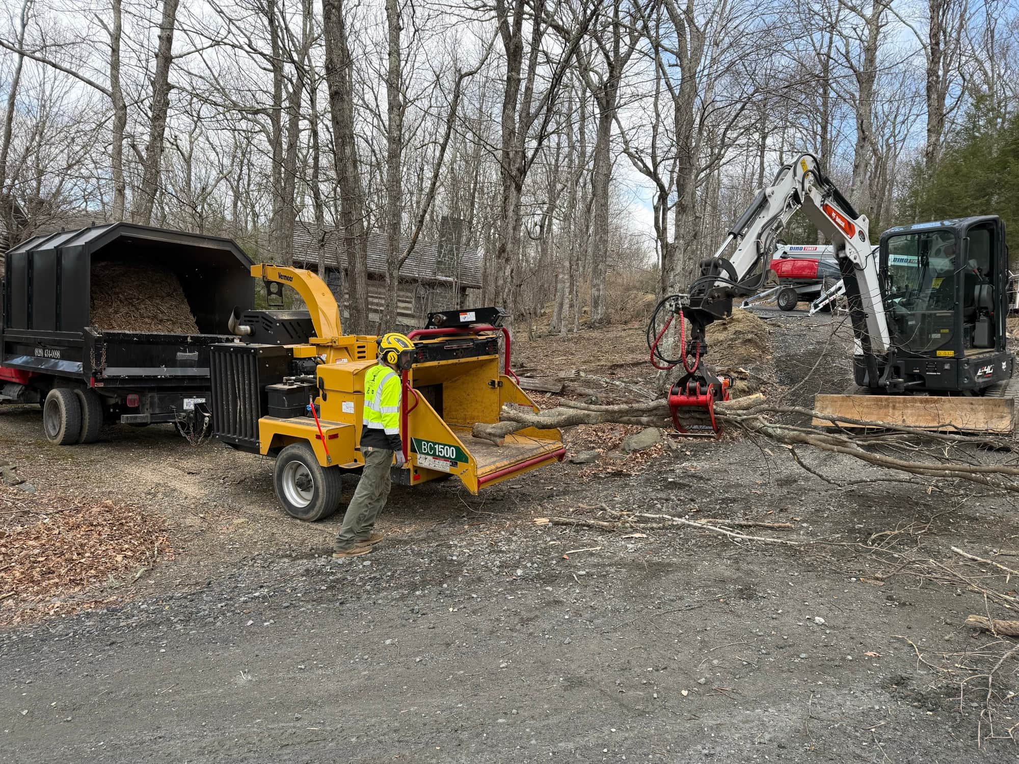 Commercial wood chipper processing brush with excavator feeding material