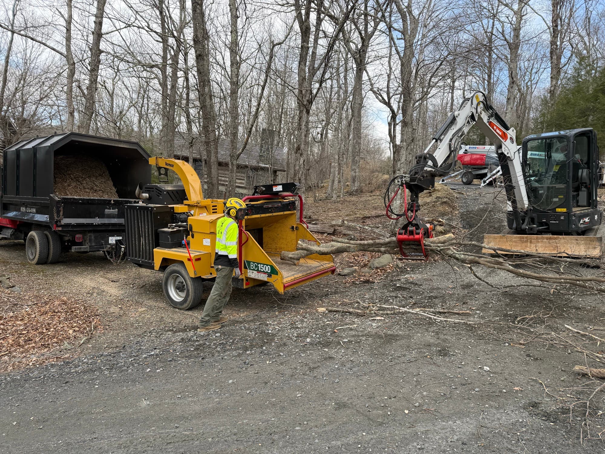 Commercial wood chipper processing brush with excavator feeding material