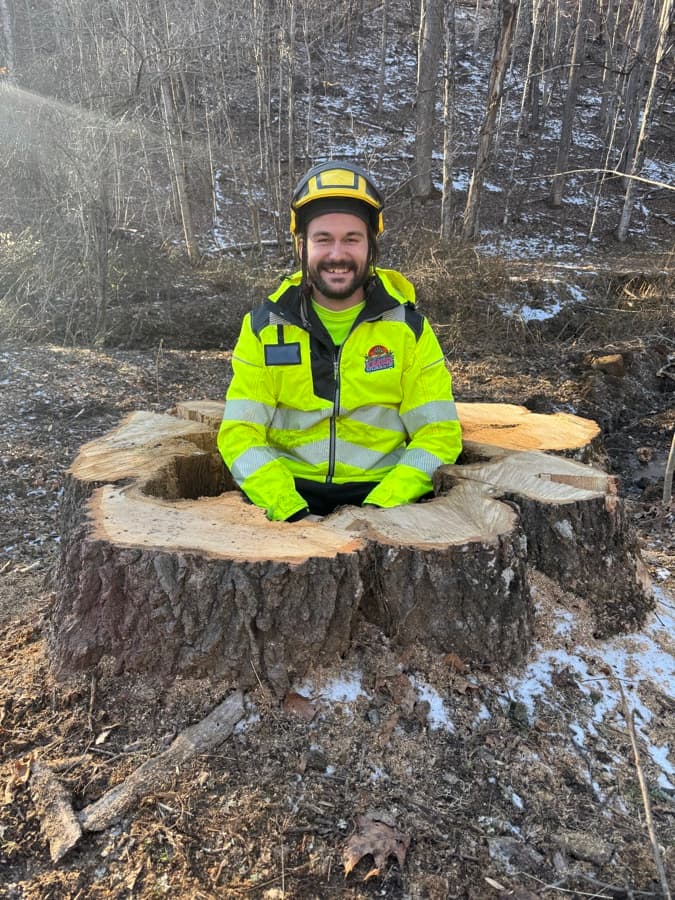 Noah Krause standing in front of a freshly cut tree stump